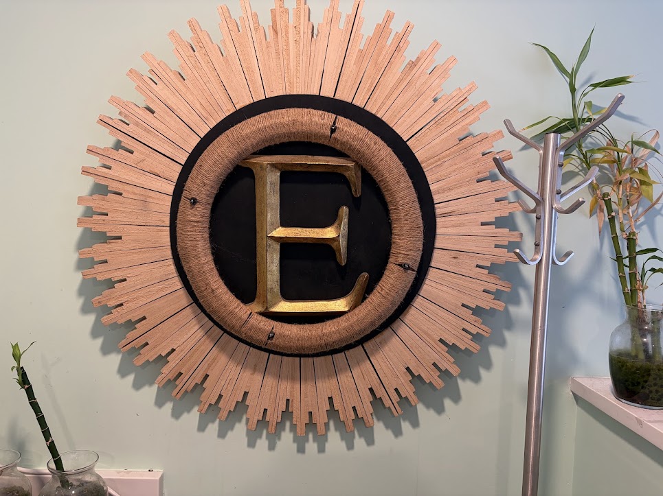 Gold letter E sunburst wall hanging in the Ella's Therapeutic Baths & Spa lobby